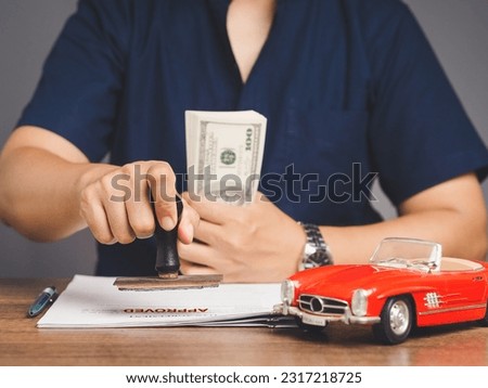 Car loan or Title loan. Businessman stamped the approved for car loan agreement while sitting at the table in the office.