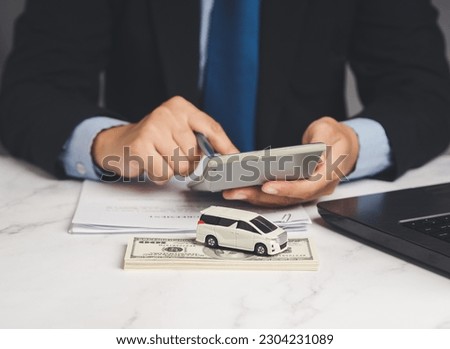 Car loan or Title loan. A Businessman using a calculator while sitting at the table. Miniature a red car model, a calculator, and a laptop on a table. Car finance and insurance concept
