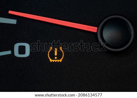 Car low tire pressure warning light. Vehicle repair, maintenance, and cold weather safety concept.
