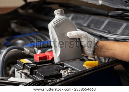 Car lubricant gallon or from gray bottle on engine background Oil change service, auto repair shop Technology and transportation industry