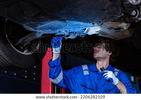 Car Machanic cheking under car to find the problem of broken car, car service, engineer working concept.
