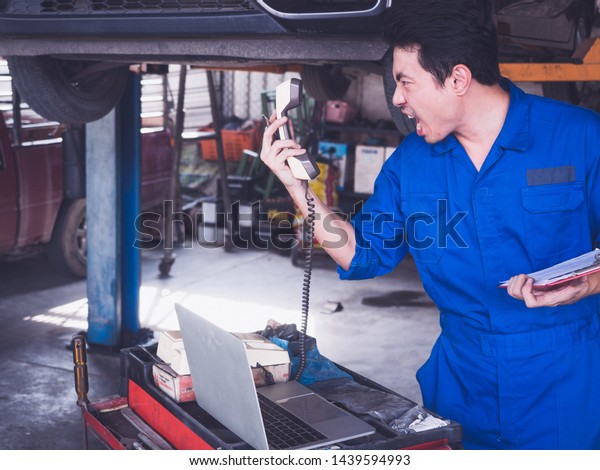 car machine man angry Yelling at the phone holding\
notepad in garage shop