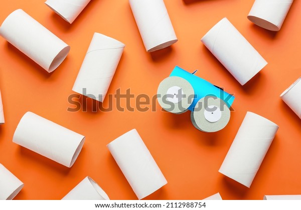 Car made of cardboard and tubes for toilet\
paper on orange background