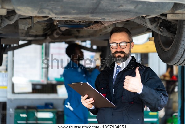 Car maintenance and automobile\
service garage. Portrait Beard Male manager with Checklist paper in\
hand at Car care and automobile service garage\
concept.
