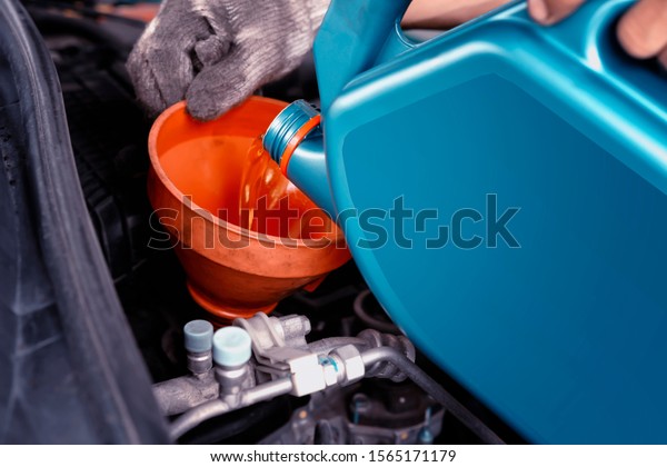 Car\
maintenance concept.Car mechanic replacing and pouring fresh oil\
into engine at maintenance service station.Auto repair technician\
pour new engine oil to replace the old\
one