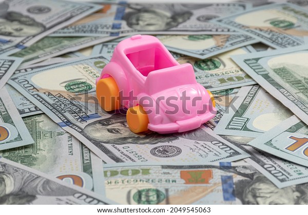 car maintenance cost buy, rent, service,\
repair and insurance concept.  pink toy car model on many hundreds\
dollars money bills\
banknotes.