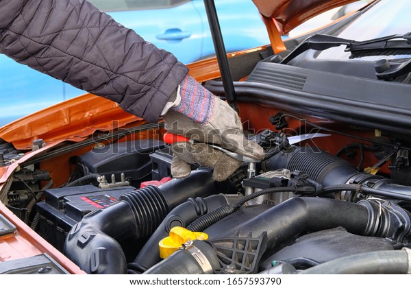 Car maintenance and repair concept. Hand of driver in\
gloves checks car using tools, open hood. Vehicle and\
transportation, close up.