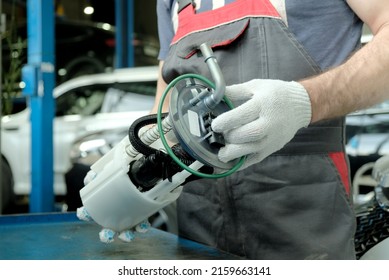 Car maintenance at a car service. An auto mechanic holds a new fuel pump in his hands. Repair of the fuel and exhaust system of the car. - Shutterstock ID 2159663141