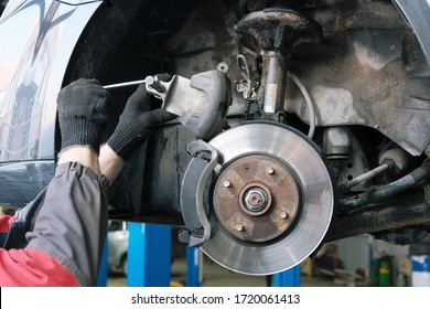Car maintenance in the service center, a close-up of the replacement of the front brake pads, compression of the brake caliper.