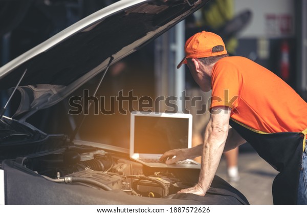 Car maintenance service, technician\
diagnose car engine failure problem by laptop\
computer.