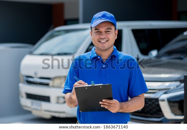 A car maintenance\
worker is checking a list of items for car maintenance for a\
workshop customer.