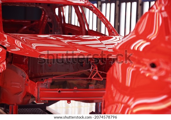 Car\
manufacturing plant, red cars on the paint\
line