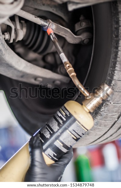 Car master mechanic repairer heating the screws\
with butane gas blow mini welding torch flamethrower burner in\
vehicle repair service