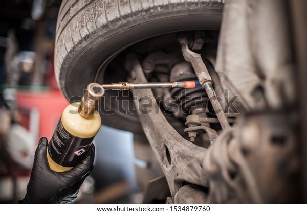 Car master mechanic repairer heating the screws\
with butane gas blow mini welding torch flamethrower burner in\
vehicle repair service