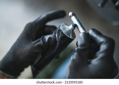 Car Mechanic Applying High Temp Disc Brake Grease On The Brake Caliper Slide Pins.