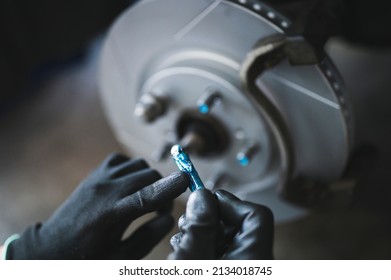 Car Mechanic Applying High Temp Disc Brake Grease On The Brake Caliper Slide Pins.