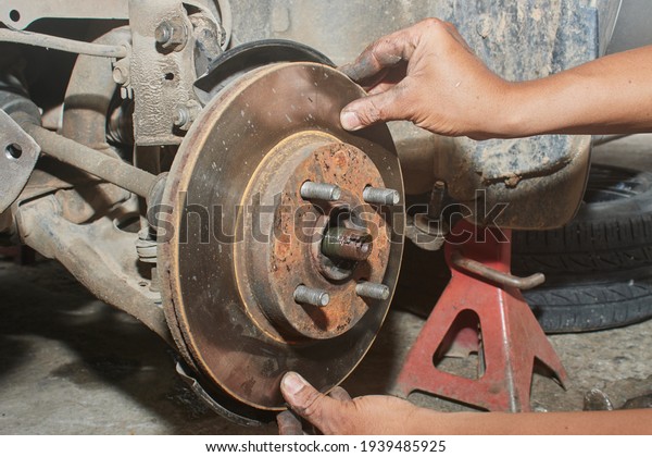 Car Mechanic Assemble Disk Brake to Front Car Wheel\
Hub in Car Repair Shop