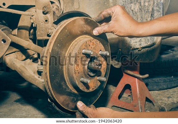 Car Mechanic Assemble Disk Brake to\
Front Car Wheel Hub in Car Repair Shop in Vintage\
Tone