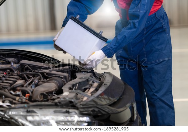 Car mechanic is changing car battery, male\
engineer is changing car battery because car battery is depleted\
maintenance concept