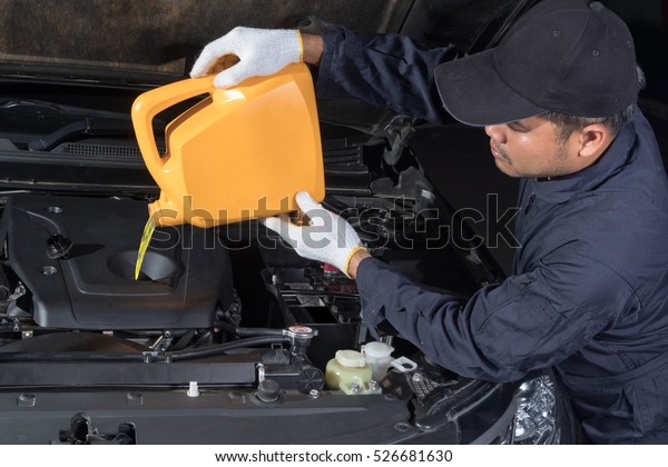 Car mechanic changing engine\
oil