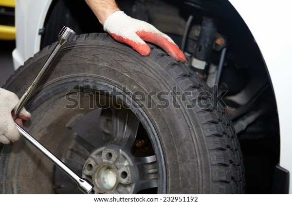 Car mechanic changing tire in professional car\
repair service