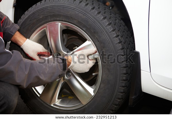 Car mechanic changing tire in professional car\
repair service