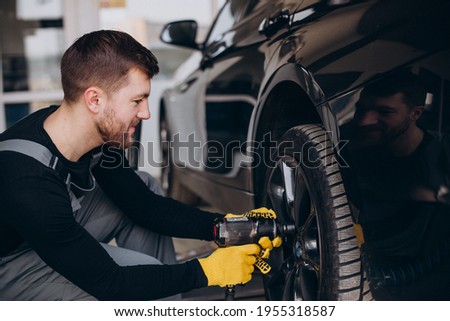 Car mechanic changing wheels in car