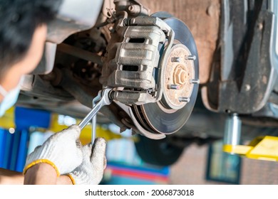 Car mechanic checking a disc brake of the vehicle for repair, in process of new tire replacement. Car brake repairing in garage at auto repair service center