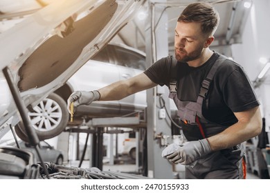 Car mechanic checking the engine oil level in the service center - Powered by Shutterstock