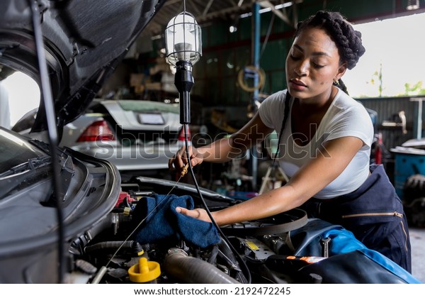 Car mechanic checking  oil quality\
the engine motor car Transmission and Maintenance Gear. car\
mechanic in an auto repair shop is checking the\
engine.