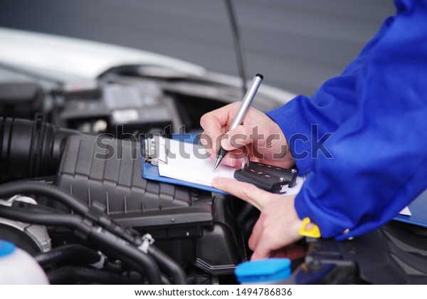 \
Car mechanic checks\
the engine of a car