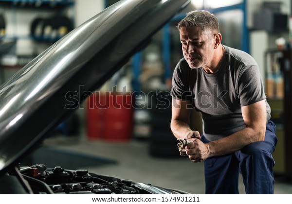 Car mechanic cleaning his hands after\
working on engine breakdown in auto repair shop.\
