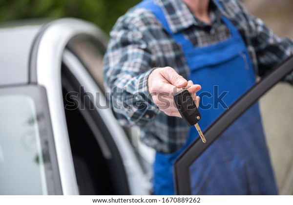 Car mechanic delivering car keys after car\
engine checking