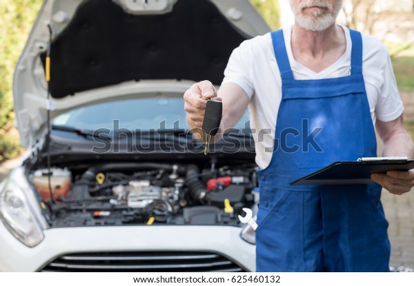 Car mechanic delivering car keys after car\
engine checking