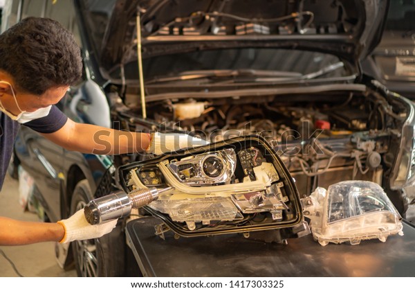 Car mechanic, doing\
cleaning, The headlight of the car, installation and turning\
headlight of modern automobile and car projector lens. Vehicle head\
xenon lamp in details.