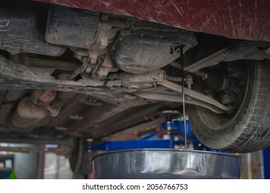 Car Mechanic Draining Automatic Transmission Fluid In Garage Services.