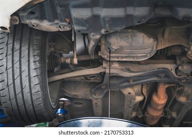 Car Mechanic Draining An Old Used Motor Oil From The Engine.