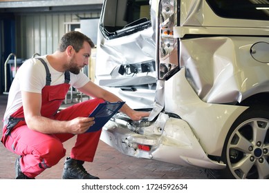 Car mechanic examines accident vehicle in a workshop for repair 