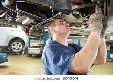 car mechanic examining car suspension of lifted automobile at repair service station - Shutterstock ID 100409044
