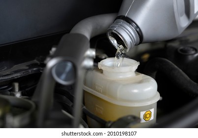 Car mechanic filling brake fluid in brake fluid reservoir.