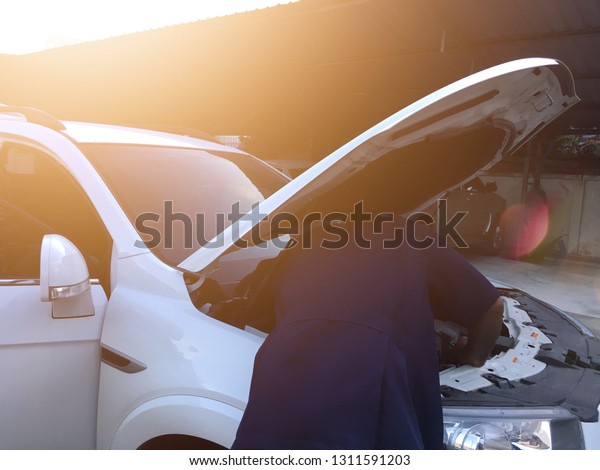 Car mechanic is  fixing car engine in auto\
service with light effect.