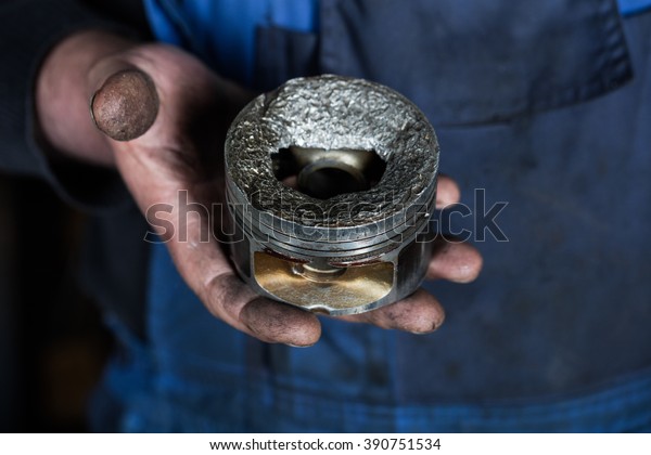 Car mechanic hand with damaged engine\
valve piston at repair service. Garage\
concept