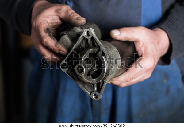 Car mechanic hand\
holding Old car starter gear, part of engine starter motor at\
repair service. Garage\
concept