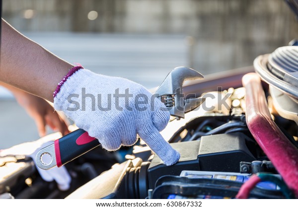Car mechanic hand with a wrench / inspection and\
maintenance car.