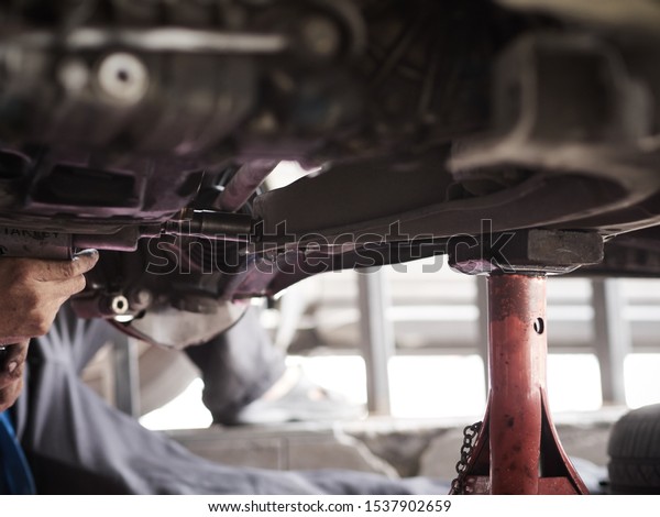 Car\
mechanic hands fixing tie rod Under the Vehicle. Mechanic\
technician working in the Professional\
Service.