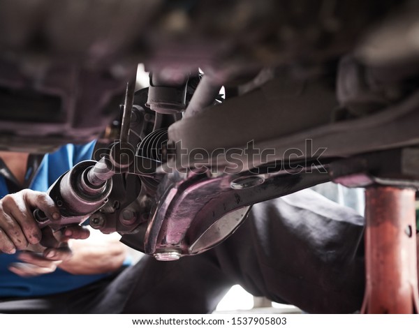 Car\
mechanic hands fixing tie rod Under the Vehicle. Mechanic\
technician working in the Professional Service.  \
