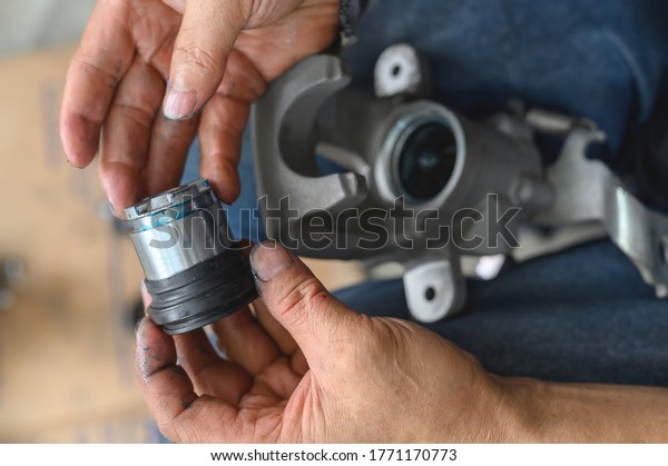 Car\
mechanic hands rebuilding car piston brake\
calipers.