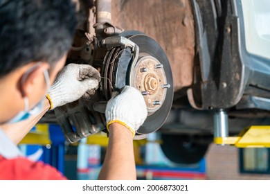 Car Mechanic Hands Replace Brakes In Garage. Mechanic Technician Worker Installing Car Wheel At Maintenance. Worker Changing Brake Disc In Auto Repair Service Center