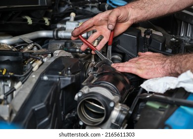 Car mechanic hands replacing engine throttle body. Mechanics workshop.
