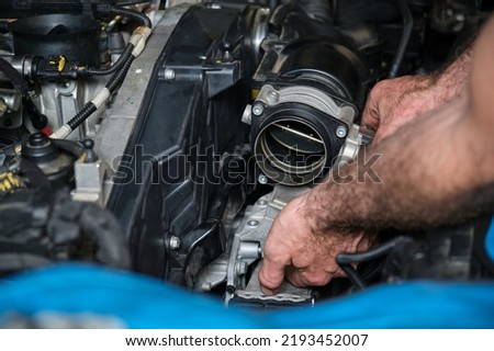 Car mechanic hands replacing engine throttle body. Mechanics workshop.